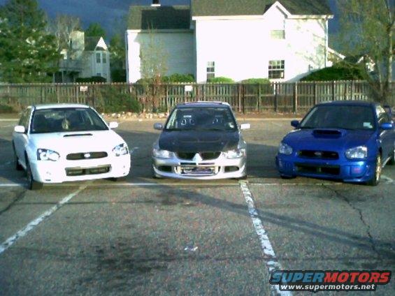2005 Subaru Impreza WRX in blue and white, parked next to a silver Mitsubishi Lancer Evolution