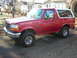 1995 Ford Bronco - Side view of a red 1995 Ford Bronco with a white removable top.