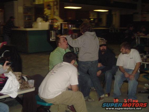 Group of guys hanging out indoors, one person is touching another's head