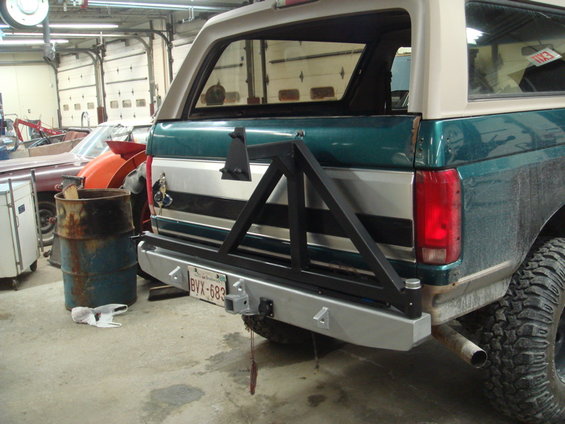 Green and tan Ford Bronco rear with aftermarket bumper and tire carrier