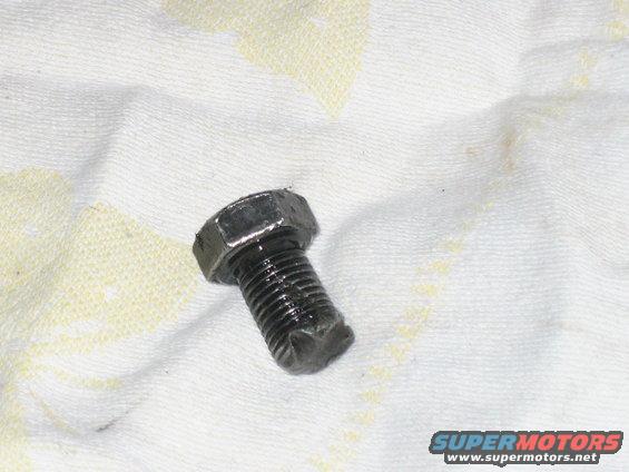 Greasy bolt on a white cloth with yellow stains. Supermotors.net logo in lower right