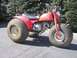 1900 Honda Big Red - A red Honda ATC 110 three-wheeler is shown from a 3/4 front angle, parked outdoors.
