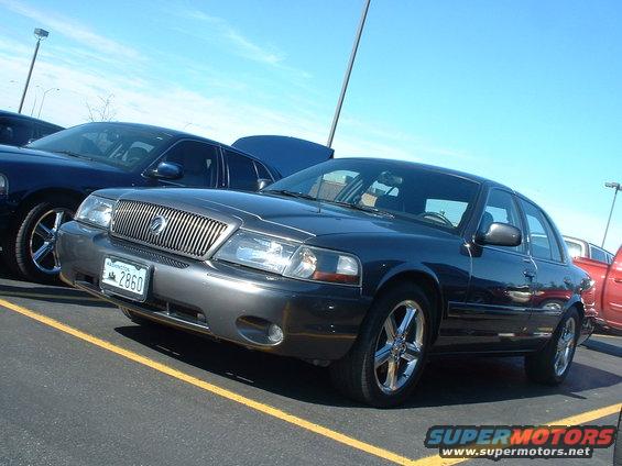 Dark sedan with chrome grille and wheels parked next to a blue sedan