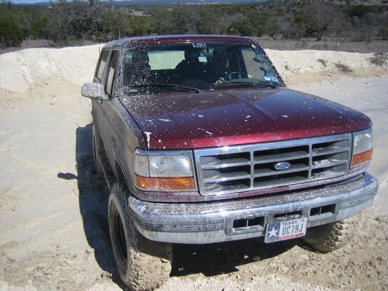 Maroon 1996 Ford Bronco covered in white splatter, front 3/4 view, off-road tires, Texas license plate DC79J