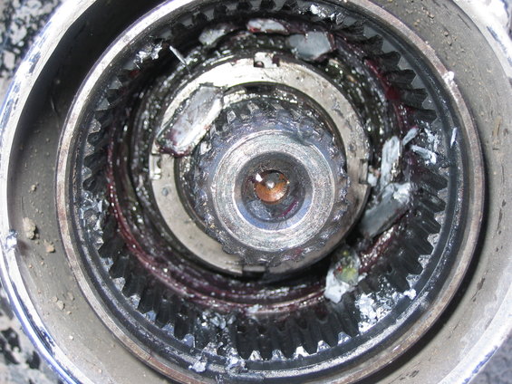 Close-up of a damaged wheel hub assembly with broken gears and grease