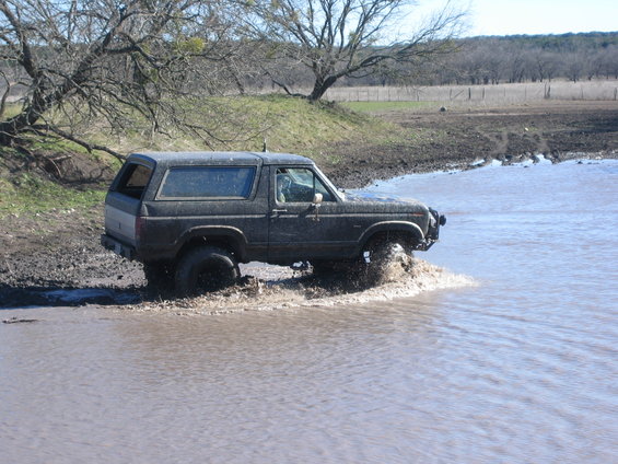 Dark SUV driving through muddy water, 1987 model year