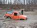 1984 Ford Bronco - This orange 1984 Ford Bronco is deeply stuck in mud with its driver's door open.