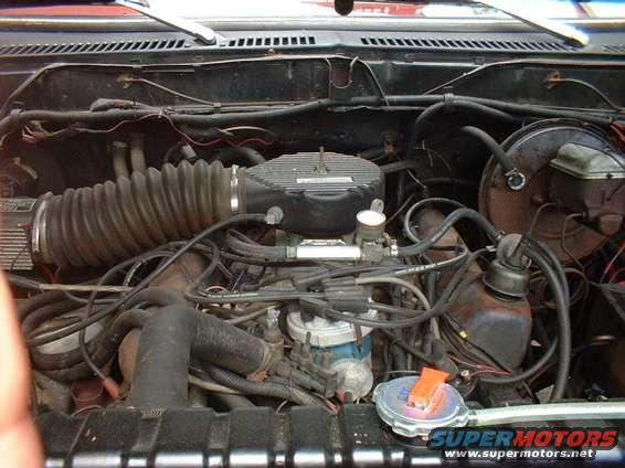 Engine bay with air intake, carburetor, distributor, and brake fluid reservoir
