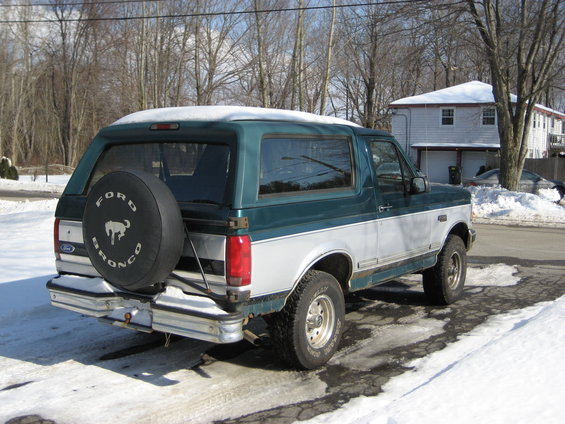 1994 Ford Bronco parked in snow, rear view with spare tire on back