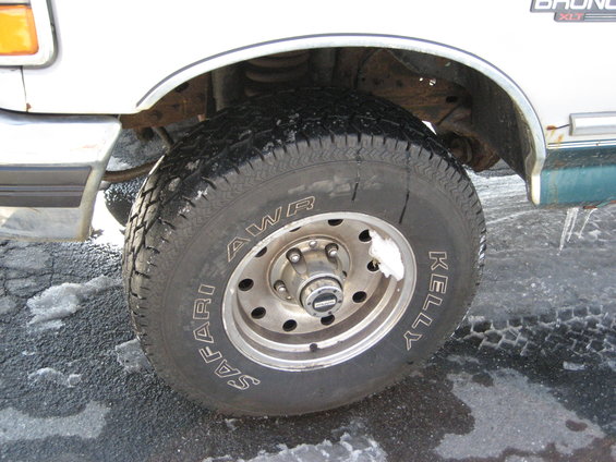 Close-up of a 1994 Ford Bronco's front wheel and fender. The tire is a Kelly Safari AWR