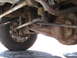 1994 Ford Bronco - Close-up view of the heavily rusted undercarriage, suspension, and differential of a vehicle.