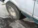 1994 Ford Bronco - The side of a 1994 Ford Bronco is shown with a tire on a wet, snowy surface, revealing some rust on the lower body panel.