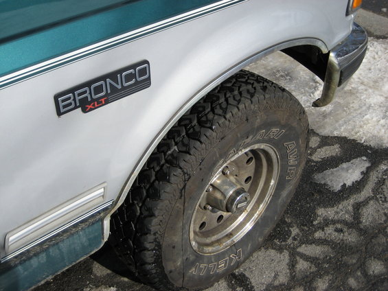 Silver and green Ford Bronco XLT fender with a knobby tire and chrome trim