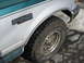 1994 Ford Bronco - Close-up of a 1994 Ford Bronco XLT's side panel and tire, showing its two-tone paint and fender badge.