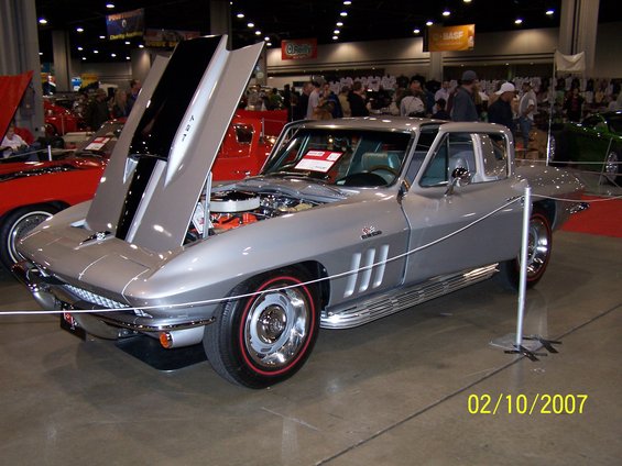 Silver 1967 Chevrolet Corvette Sting Ray with hood open, red-line tires, and side pipes