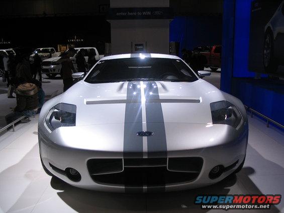 White Ford GT with grey racing stripes, front view, at an auto show