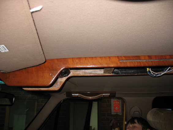 Overhead console wood trim with exposed wires and a sun visor