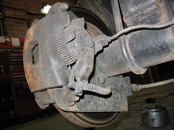 close-up of a rear drum brake assembly with brake lines and springs