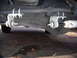 1992 Ford Bronco - Close-up view of the steering linkage and shock absorber mounted to the vehicle's undercarriage.