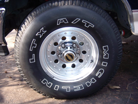 Close-up of a Michelin A/T tire on a chrome wheel with a gold center cap