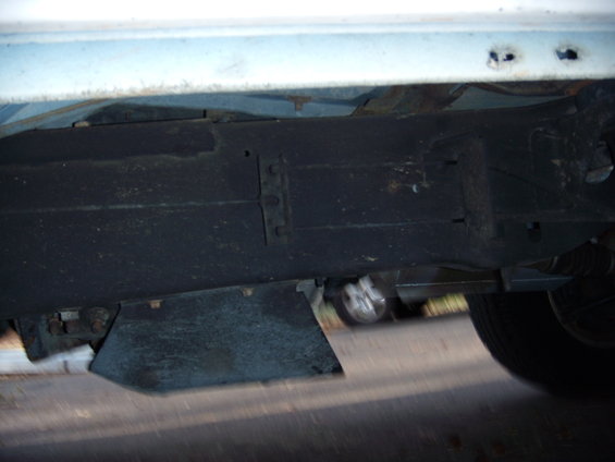 Undercarriage view of a vehicle, showing frame and part of a tire