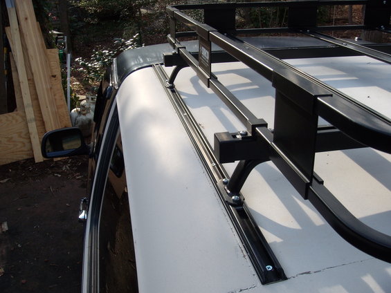 White vehicle roof with black roof rack rails and crossbars, viewed from the side