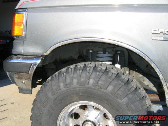 1989 Ford Bronco front fender, chrome bumper trim, and large off-road tire
