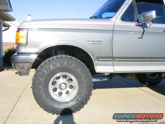 Silver Ford Bronco with red pinstripes, lifted suspension, and large tires