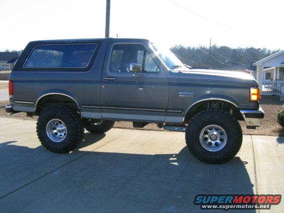 Gray Ford Bronco with lifted suspension and large tires parked on a driveway