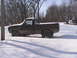 1980 Dodge Magnum - A dark pickup truck is partially buried in snow, with snow also covering its roof and windows. The vehicle appears to be a 1980 model.