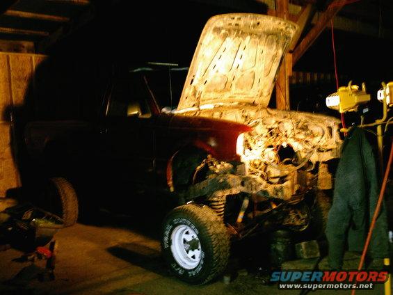 Truck in garage with hood up, engine compartment visible, front wheel and fender shown