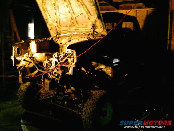 Truck with engine exposed, hood up, in a garage