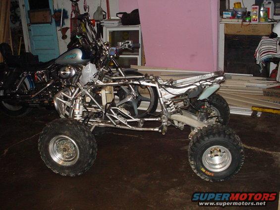 ATV frame with a motorcycle engine installed, parked next to a motorcycle