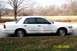 2003 Ford Crown Victoria - This 2003 Ford Crown Victoria is seen from the side, parked on a street with dry grass and trees in the background.