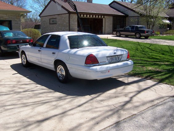 White Ford Crown Victoria parked in driveway, another car in background