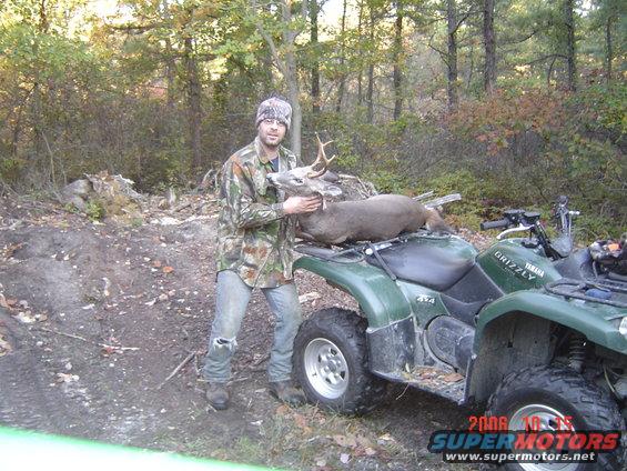 Green Yamaha Grizzly ATV with a man holding a deer on its rack