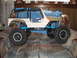 1984 Ford Bronco - This remote-controlled Jeep features a roll cage and oversized tires, displayed on a patterned surface.