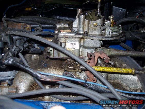 Close-up of a carburetor with various hoses and wires attached