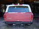 1978 Ford Bronco - The rear of a red and white Ford Bronco is shown, a white camper shell and a black bumper with a tow hitch.