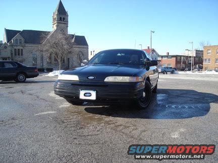 Black 1992 Ford Crown Victoria parked outside a building with a tower