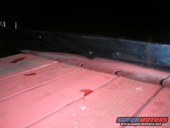 Red painted wooden planks under black reflective surface