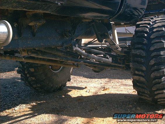 Undercarriage view of a lifted off-road vehicle with large tires and suspension components visible
