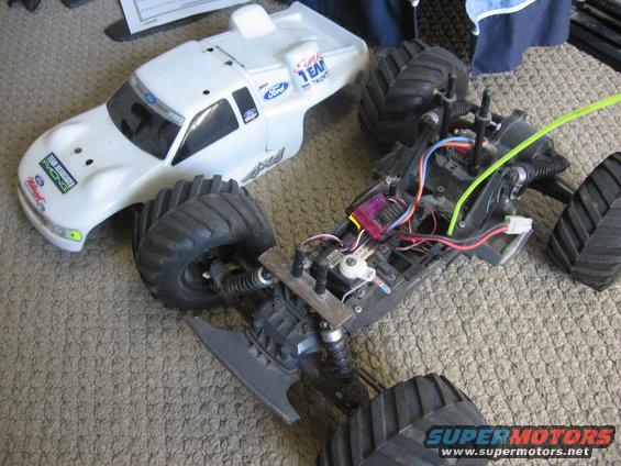 White remote control truck body with Ford logos next to a disassembled chassis with large tires