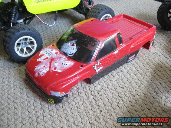 Red RC truck body with white and red decals, next to a yellow RC vehicle