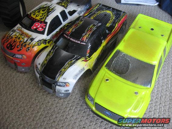 Three remote control truck bodies, two with flame graphics and one neon yellow