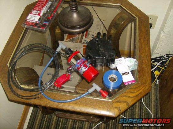 MSD ignition coil, distributor cap, spark plug wires, and blue electrical tape on a glass-top table