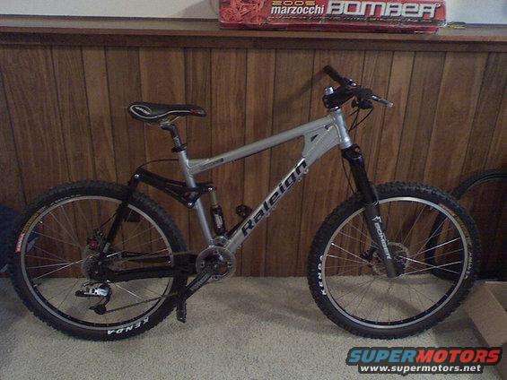 Silver Raleigh bicycle with black suspension fork and wheels, parked indoors