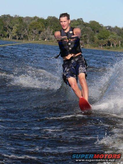 guy waterskiing on a lake, trees in background