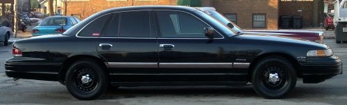 Black sedan with tinted windows and steel wheels, seen from the side