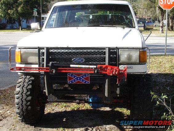 White 1989 Ford Bronco front view with Hi-Lift jack and Confederate flag plate